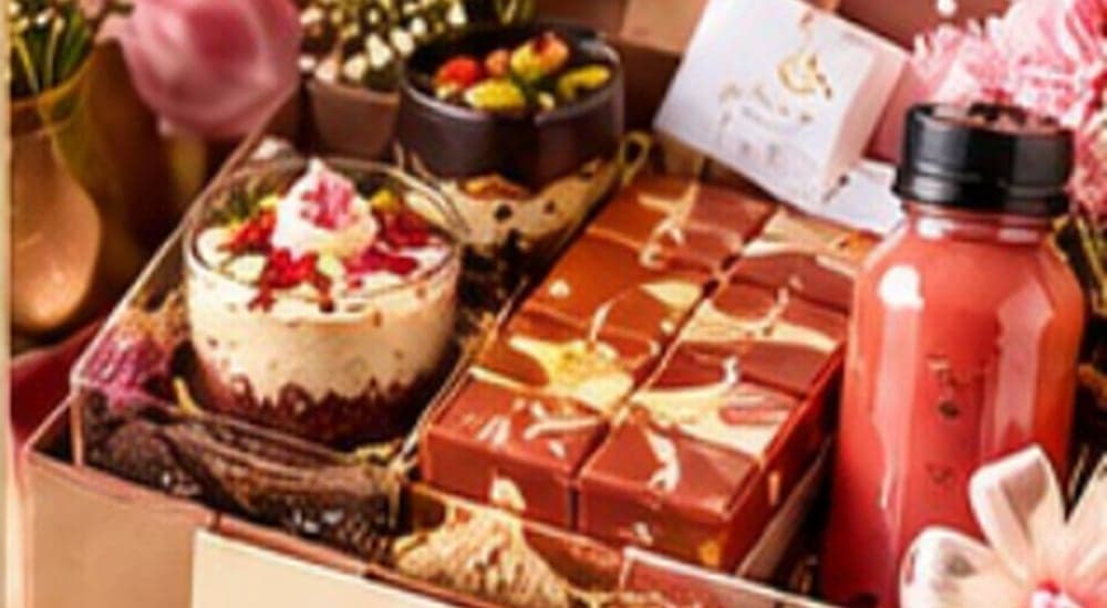 A curated gift box with chocolates, a dessert cup and a juice bottle